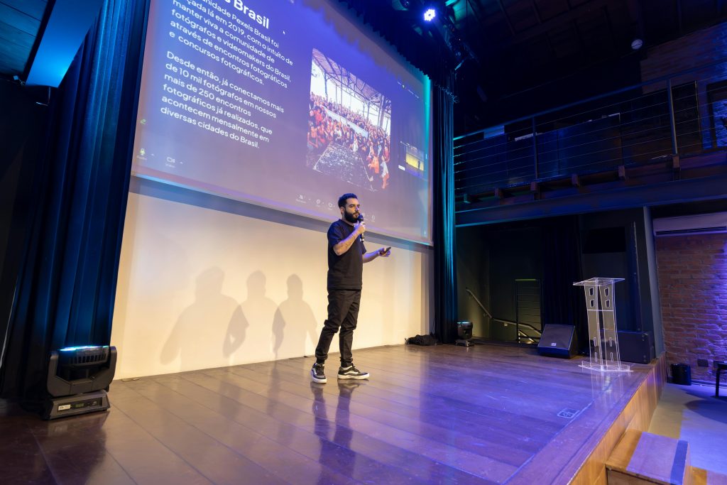 Speaker presenting at a conference with a projected presentation slide on screen.